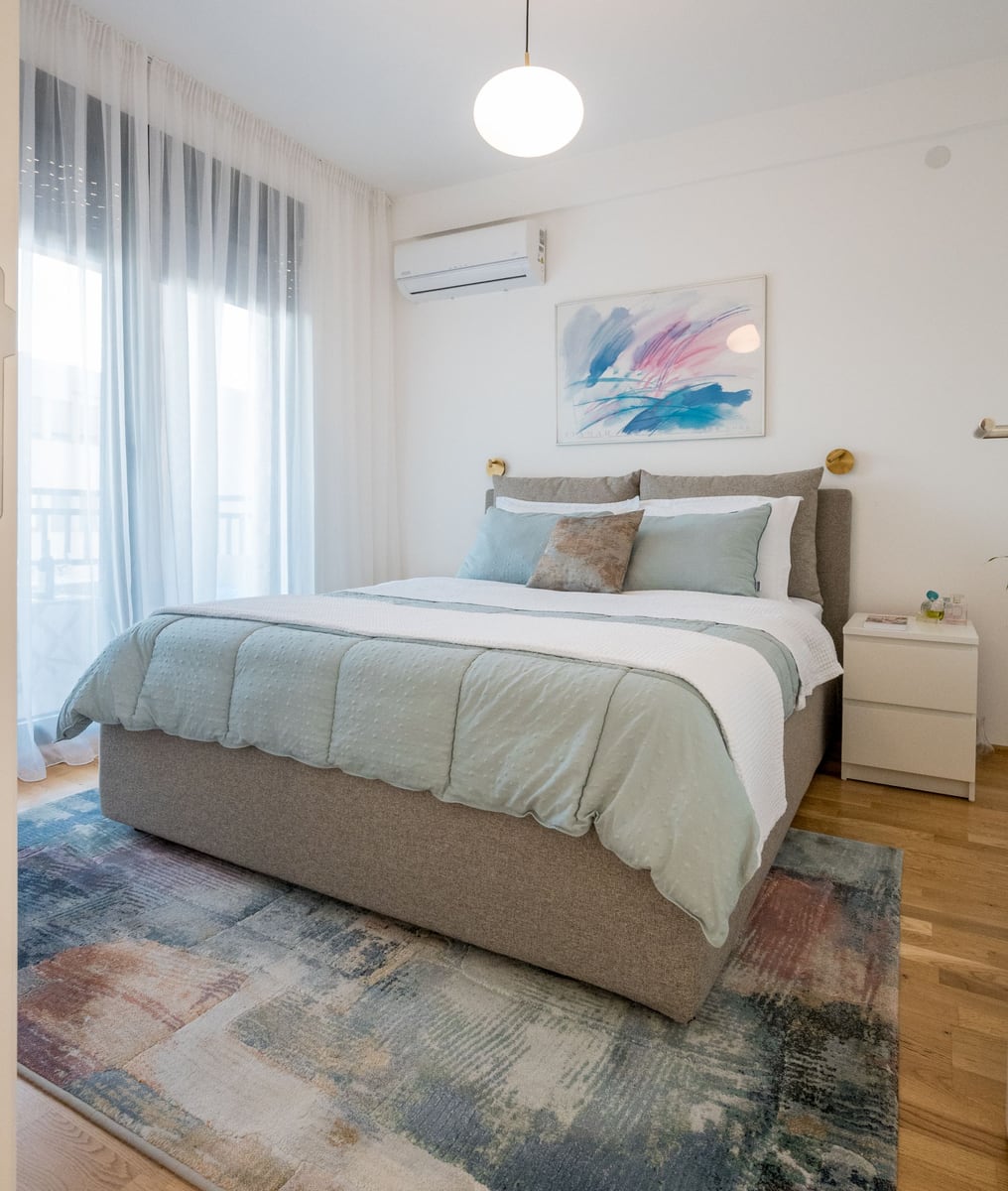 Bright bedroom with a double bed in an apartment in Tivat, Montenegro: modern interior, parquet flooring, and balcony access.