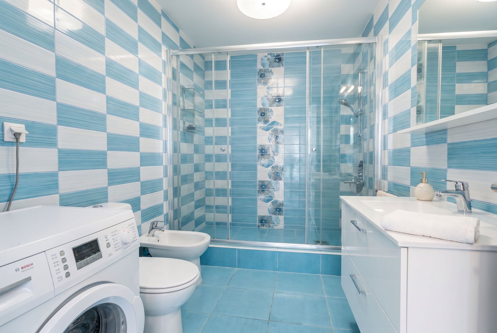 Bathroom in an apartment in Kumbor, Montenegro: shower cabin, Bosch washing machine, bidet, and light-toned finishes.