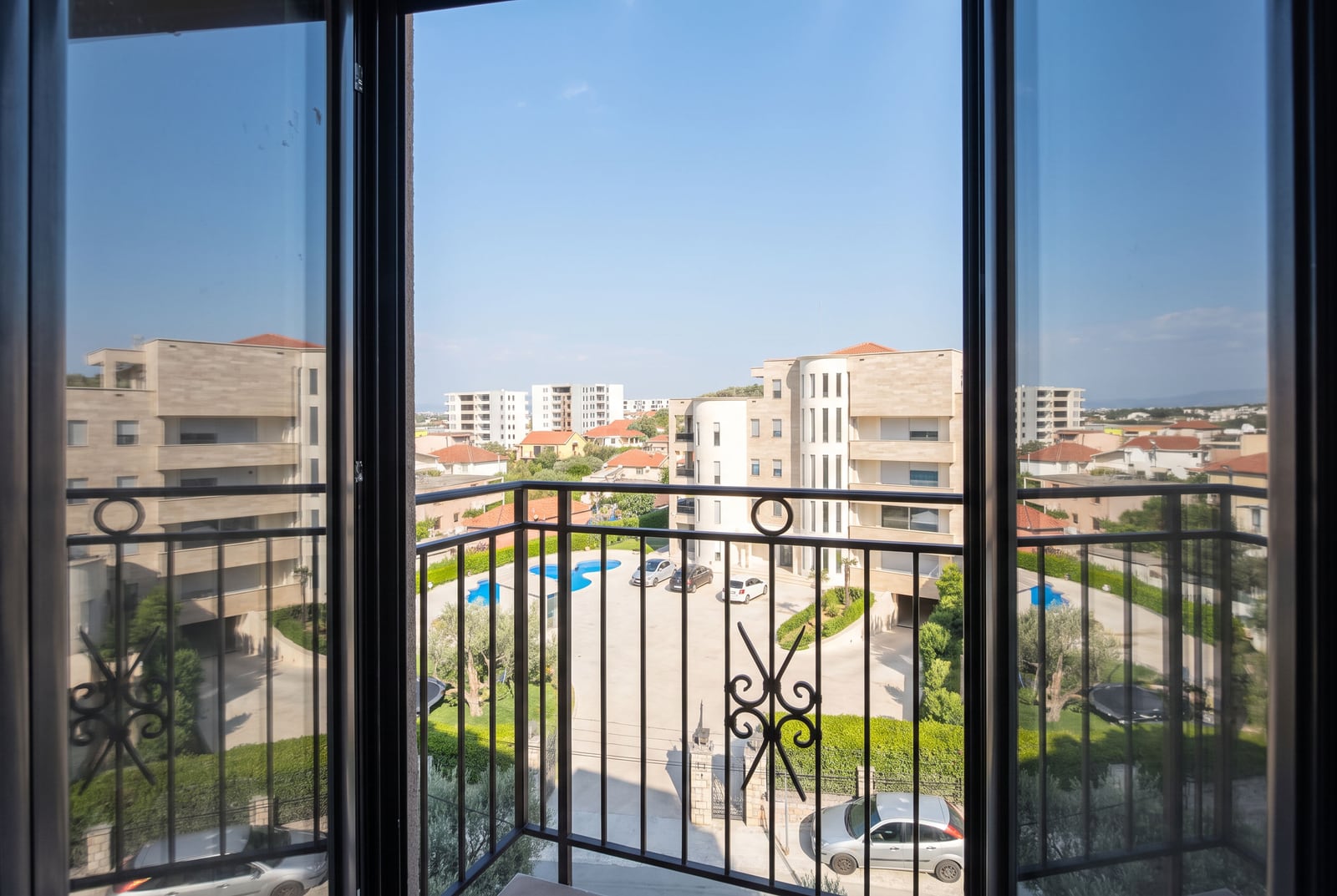 View from the apartment balcony overlooking the pool and modern buildings in the residential complex in the city of Bar, Montenegro.
