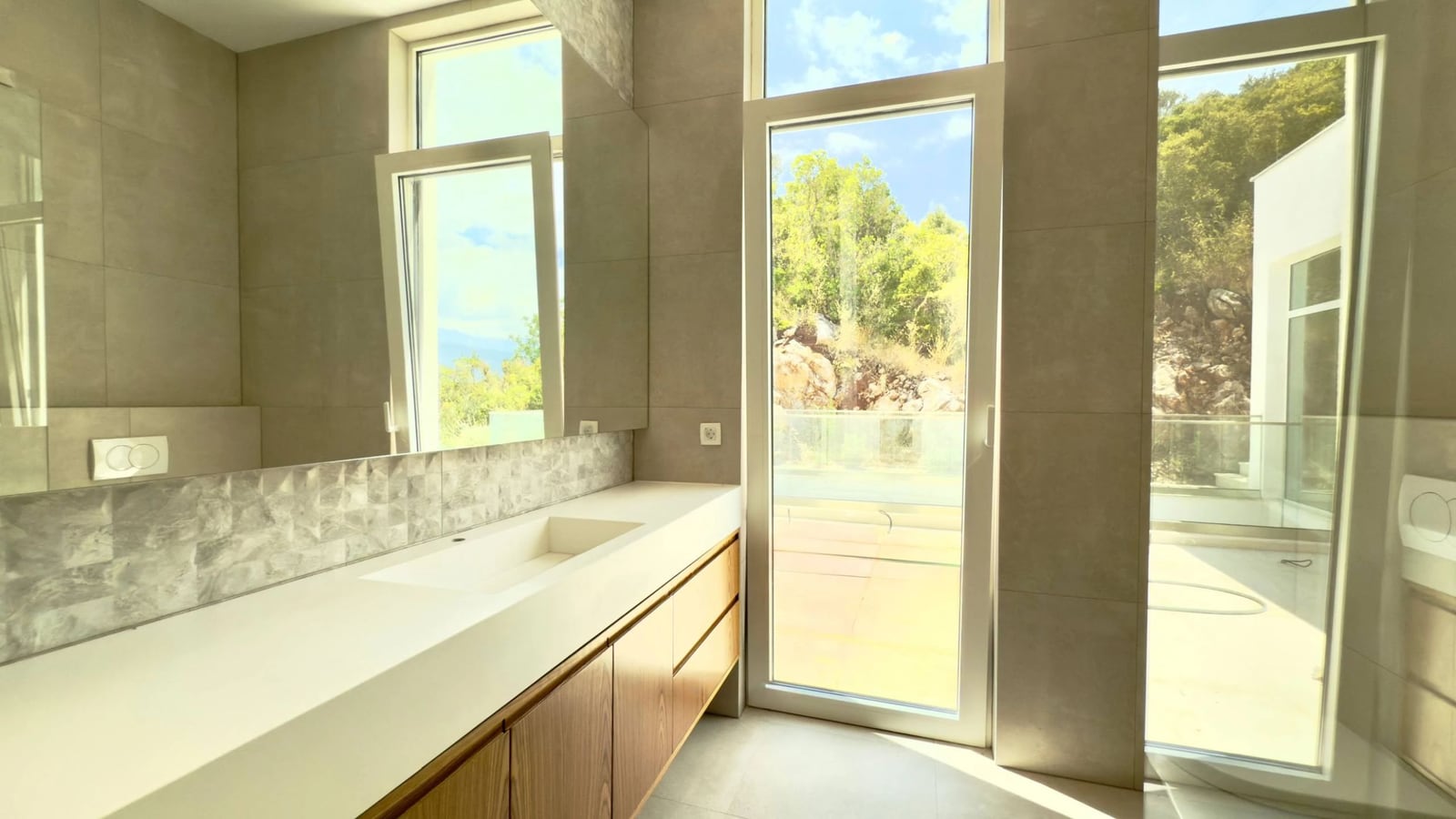 Modern bathroom with panoramic windows and a terrace in a villa in Krašići, Montenegro. High-quality finishes.