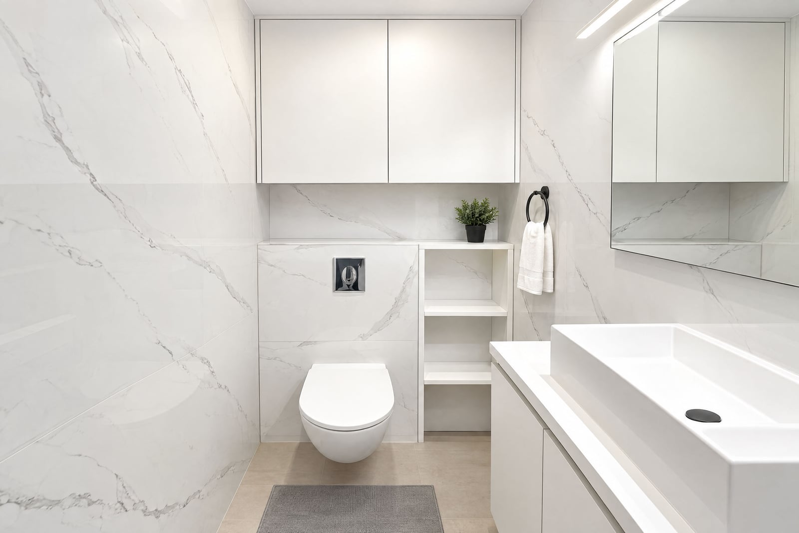 Modern white bathroom featuring a wall-mounted toilet, marble tiles, and a rectangular sink.