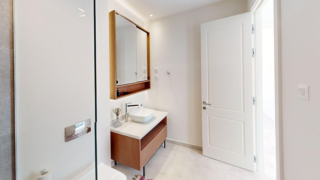 Modern bathroom with a wooden vanity and mirror in an apartment at Lustica Bay, Luštica, Montenegro.
