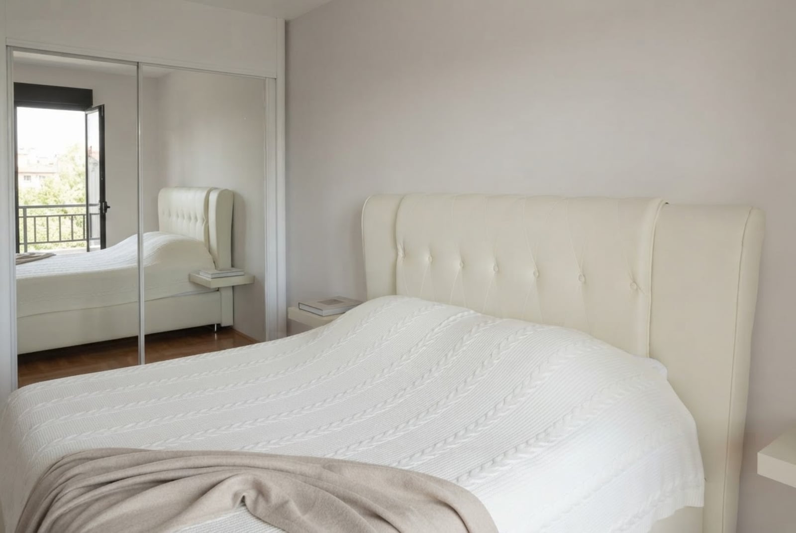Bright bedroom with a double bed and a mirrored wardrobe in an apartment in Budva, Montenegro, view of the balcony.