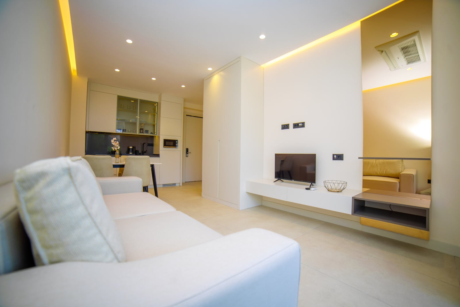 Modern living room with kitchen in an apartment in Bečići, Montenegro: bright interior, built-in furniture, and TV area.