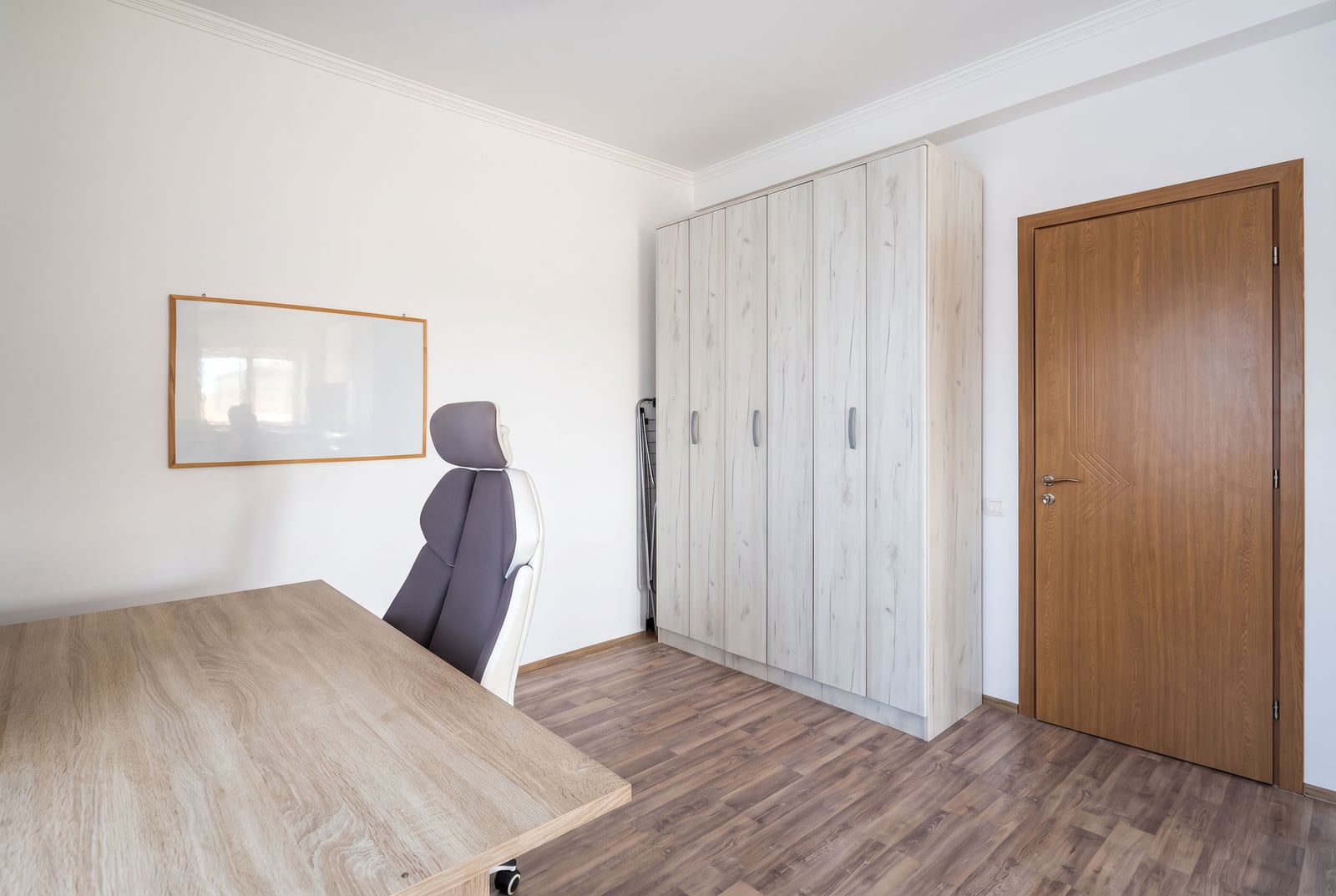 Workspace in the bedroom of an apartment in Tivat, Montenegro: desk, chair, light-colored wardrobe, and laminate flooring.