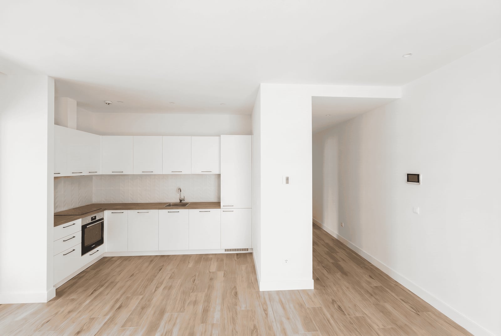 Modern white kitchen with wooden flooring in an apartment within a residential complex in Luštica, Montenegro.