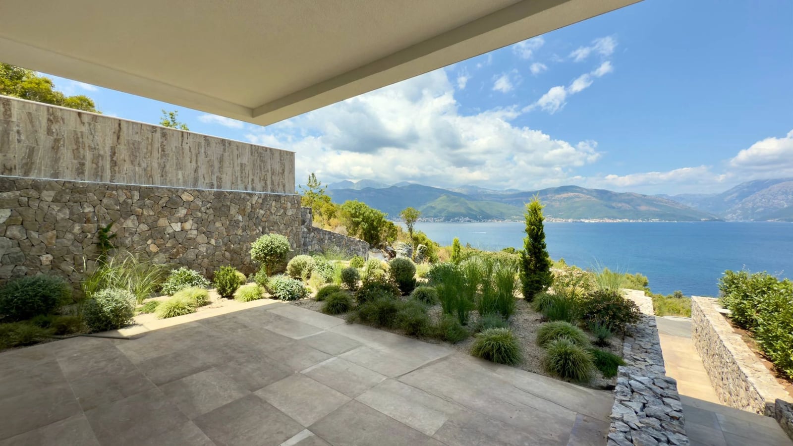 Villa terrace in Krašići, Montenegro: stone finishes, landscaping, and panoramic sea and mountain views.