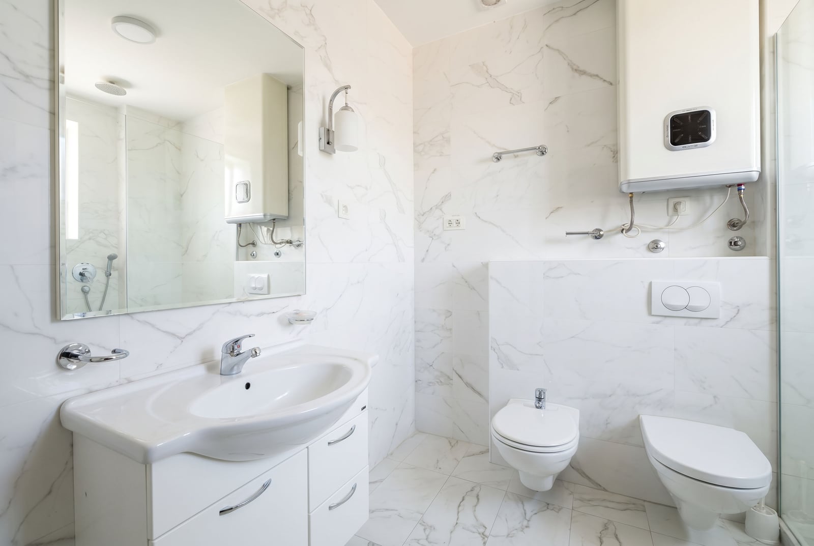 Modern bathroom in an apartment in Bečići, Montenegro: light marble-effect tiles, sanitary ware, and a water heater.