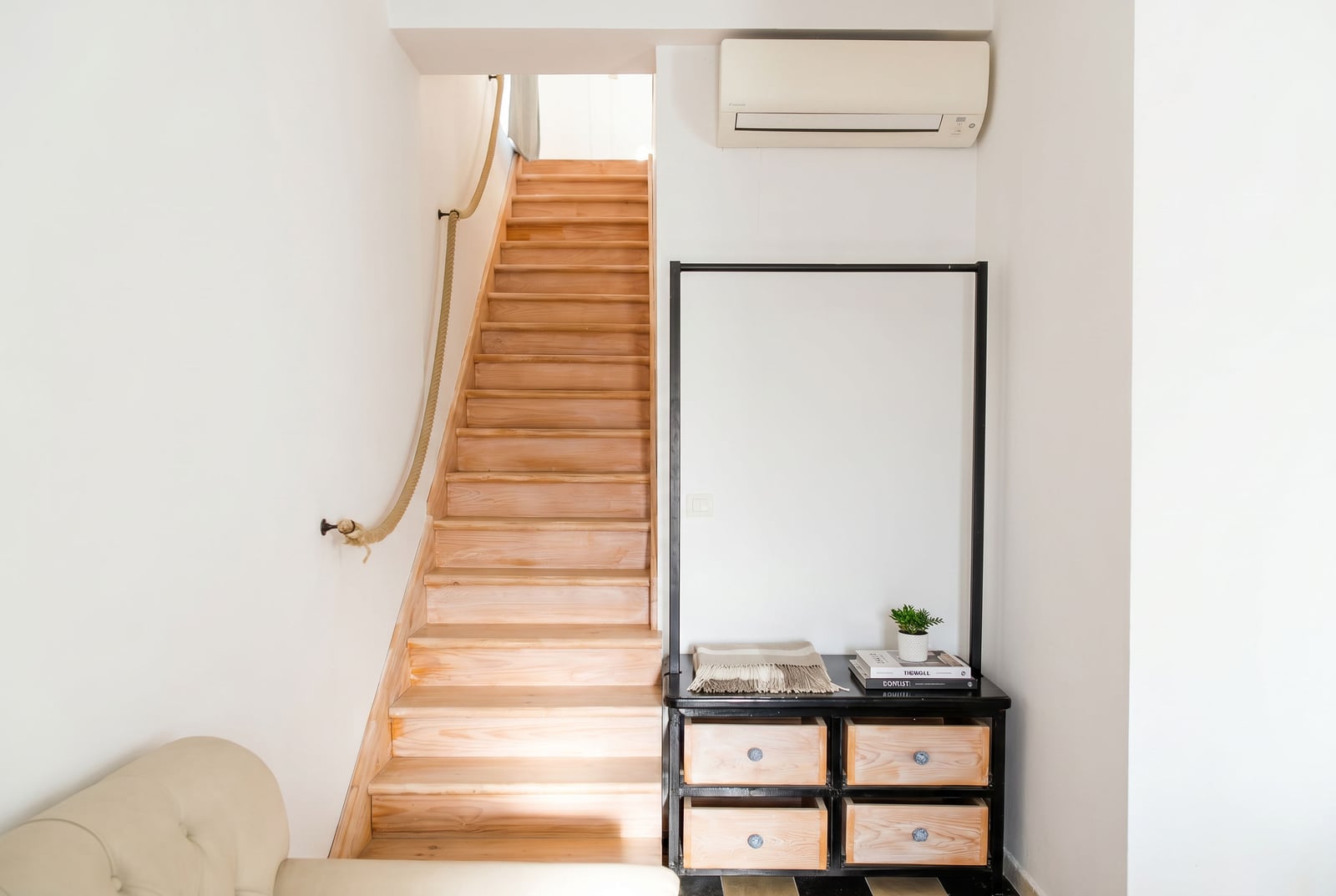Wooden staircase with a rope handrail in the interior of an apartment in Risan, Montenegro, featuring a chest of drawers and an air conditioner.