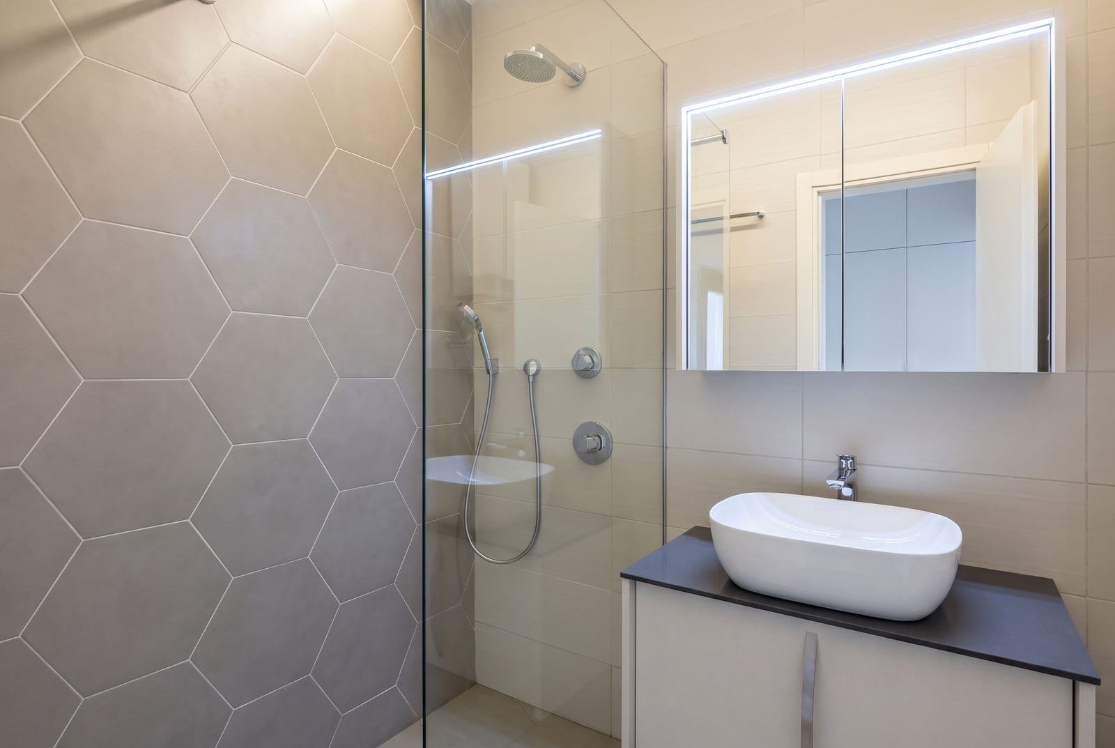 Modern bathroom in an apartment in Dobrota, Montenegro: walk-in shower, honeycomb tile, and a stylish vanity with sink.
