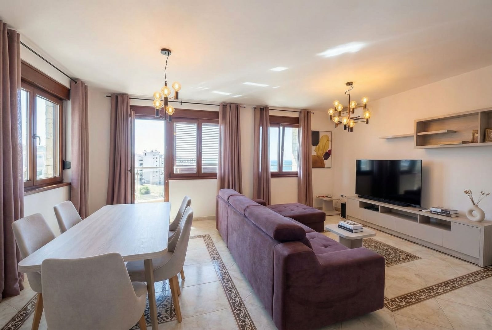 Bright living room with a purple sofa and dining area in an apartment in Bečići, Montenegro, with a sea view.