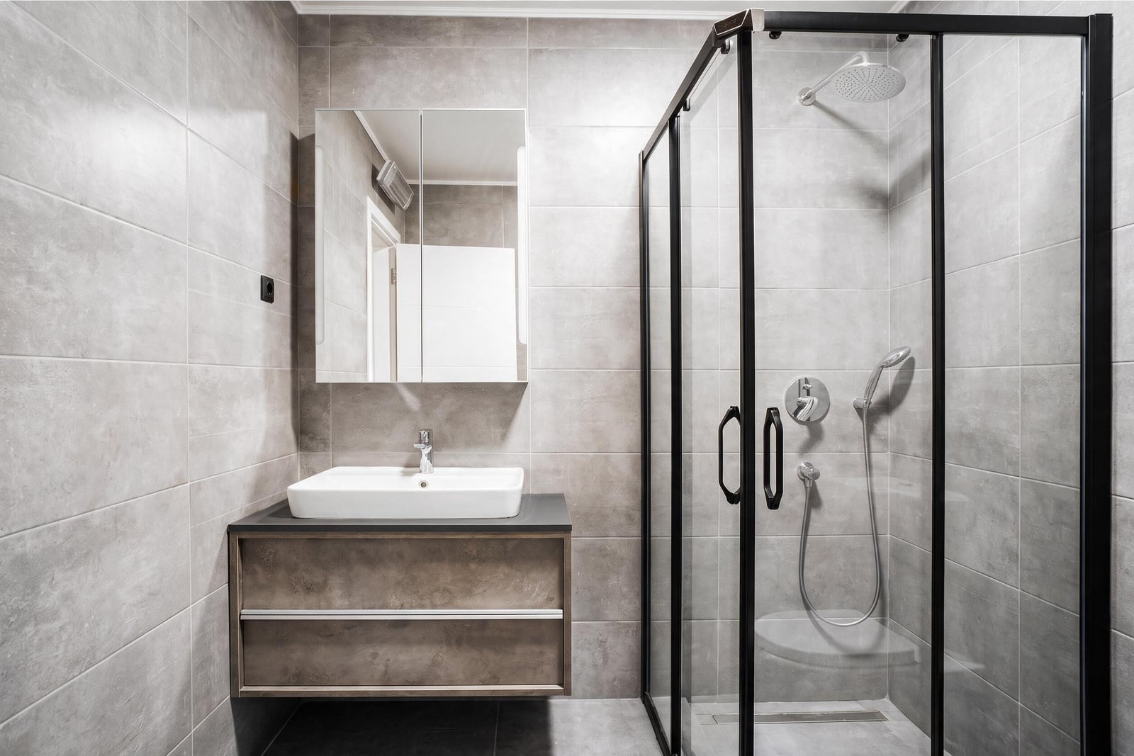 Modern bathroom with a shower cabin, sink, and gray tile in an apartment in Tivat, Montenegro