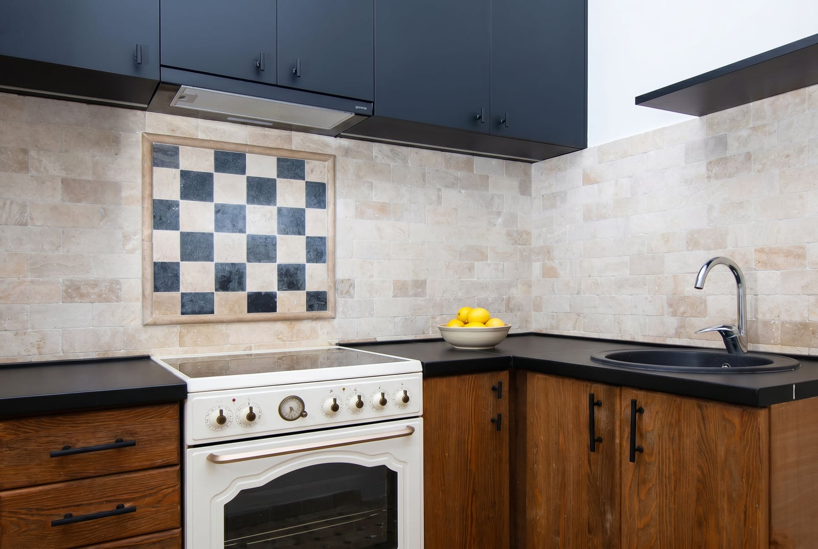 Modern kitchen in an apartment in Risan, Montenegro: wooden facades, black countertop, and Provence-style tiles.