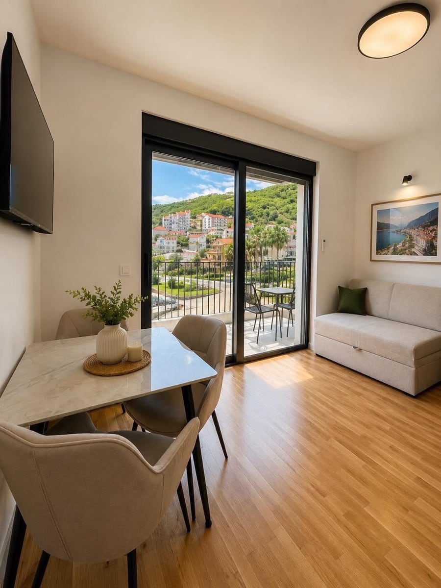 Living room with dining area and balcony in a residential complex, Herceg Novi, Montenegro: modern interior, mountain view.