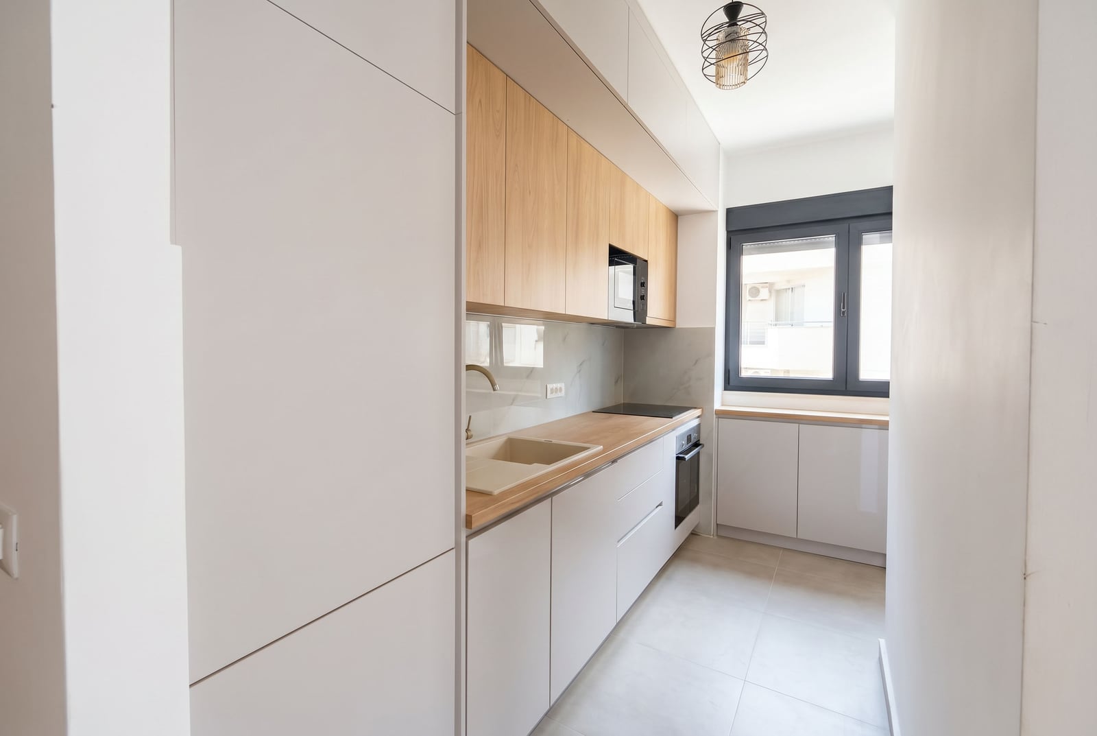 Modern kitchen in a Budva apartment, Montenegro: light-colored cabinetry, built-in appliances, and a wood-effect countertop.