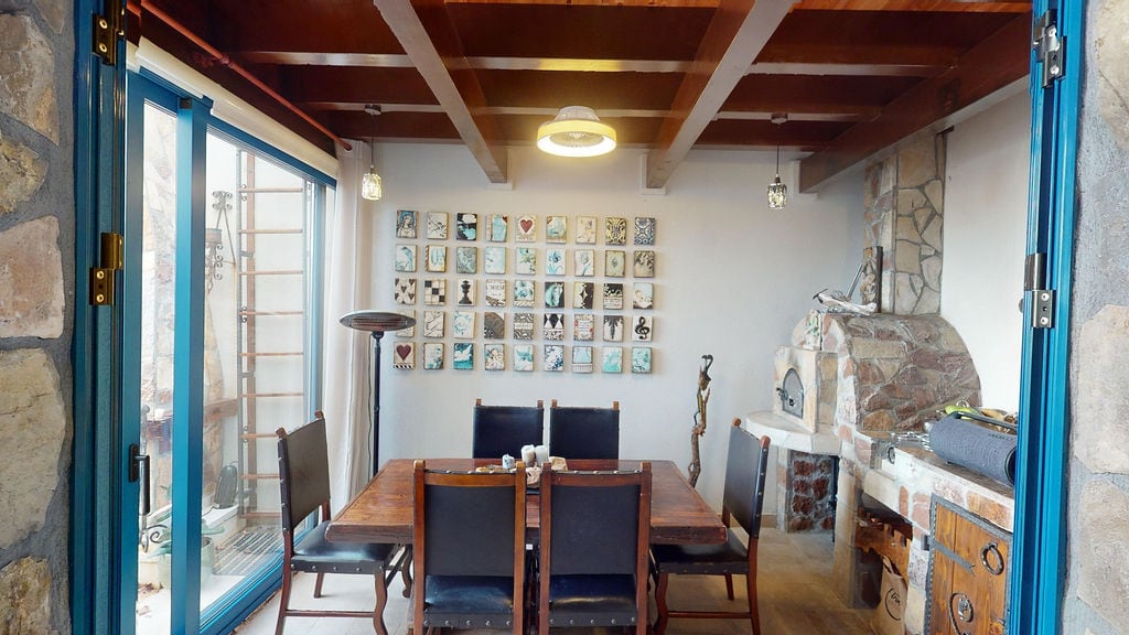 Living room with dining area in a townhouse, Luštica, Montenegro: wooden ceiling, stone fireplace, and wall decor.