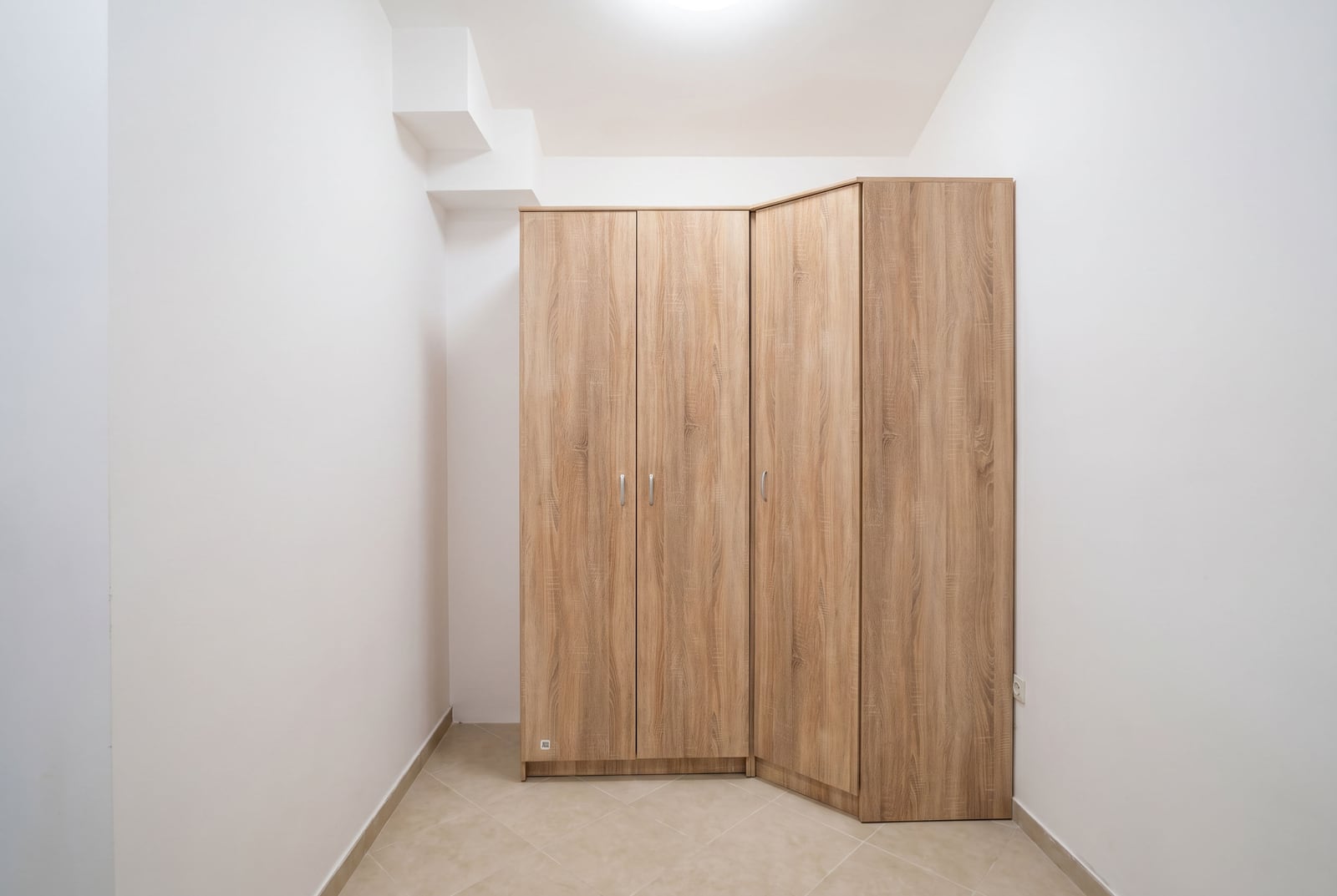 Built-in wooden corner wardrobe in a bright bedroom of an apartment in Budva, Montenegro.