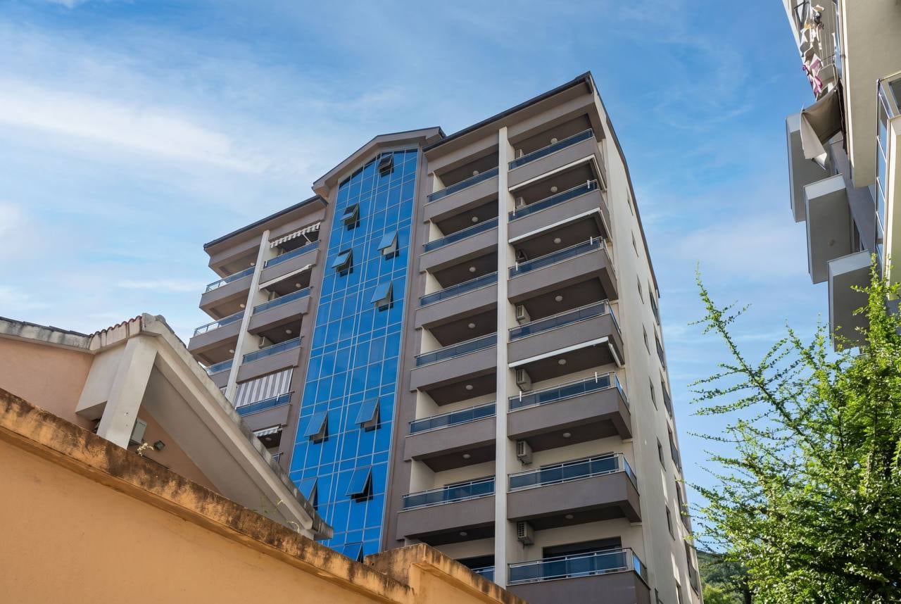 Modern multi-story residential building with panoramic glazing and balconies in the city of Budva, Montenegro.