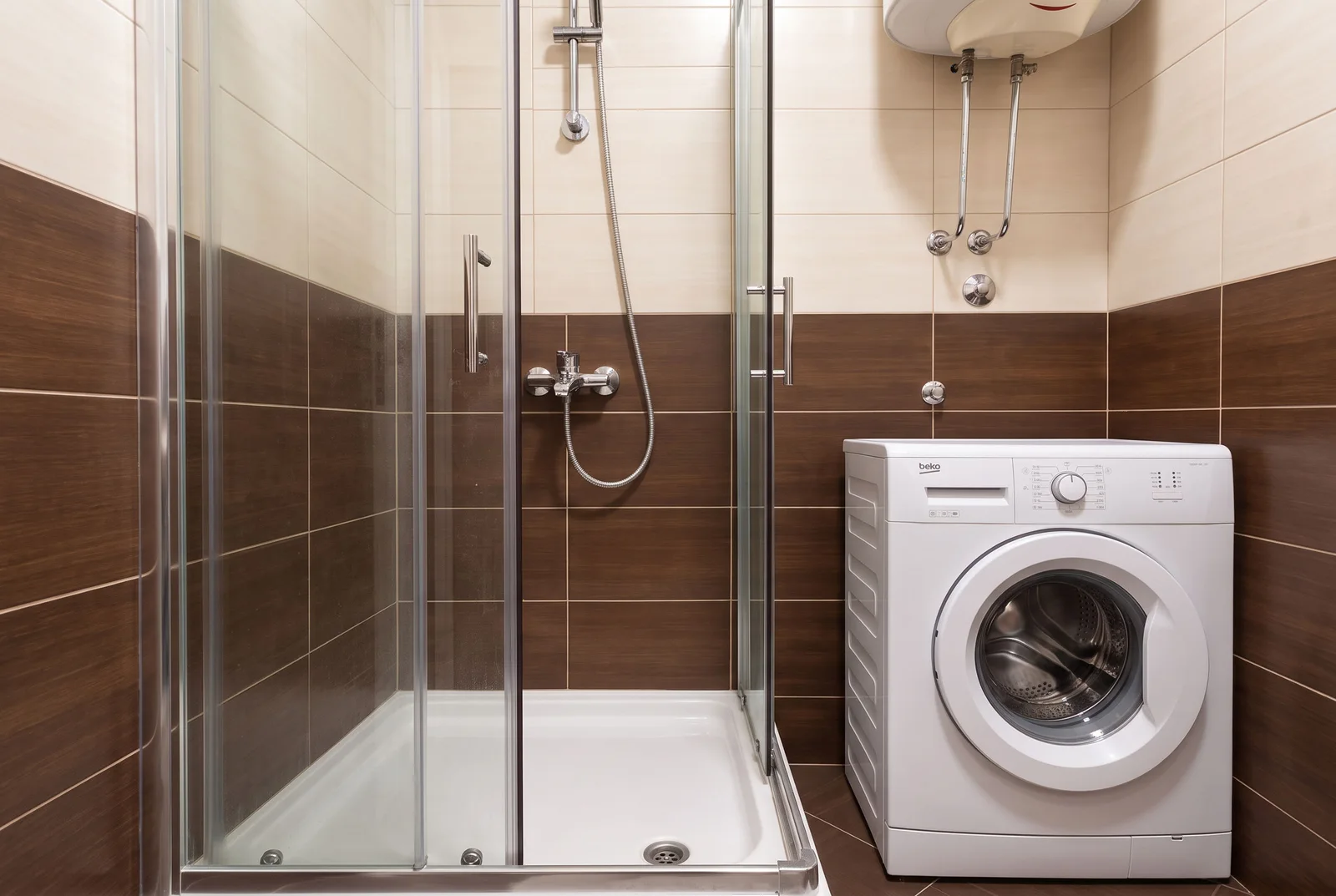 Bathroom featuring a glass shower enclosure, white washing machine, and wall-mounted water heater.
