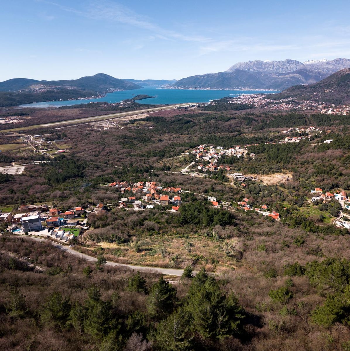 Panoramic view of a land plot in Kotor, Montenegro, with a view of the mountains, airport, and Tivat Bay.