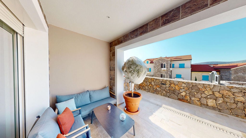 Cozy terrace with soft seating in the Luštica residential complex, Montenegro: view of stonework and mountains.