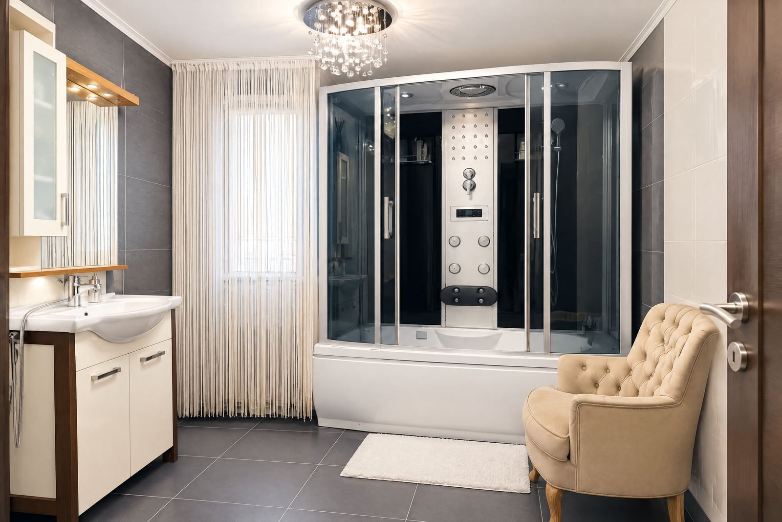 Modern bathroom featuring a large shower cabin, vanity sink, and a beige upholstered armchair.