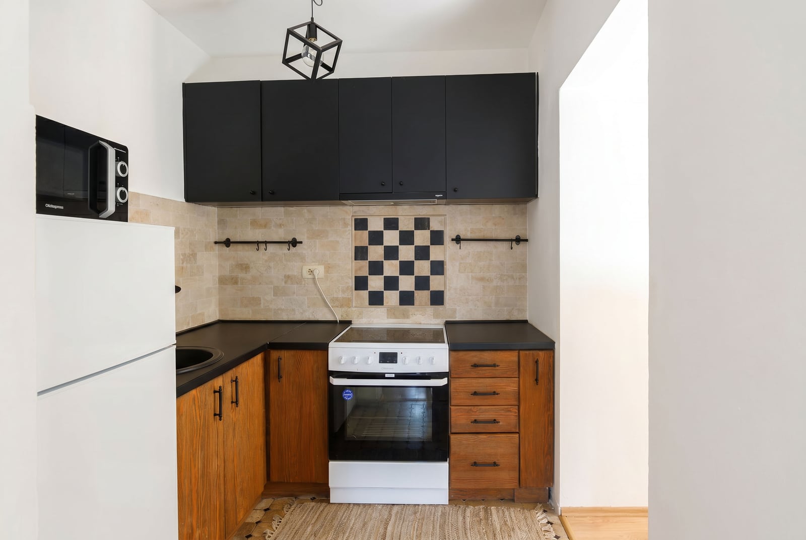 Compact kitchen in an apartment in Risan, Montenegro: black fronts, wooden cabinets, stove, and tiled backsplash.