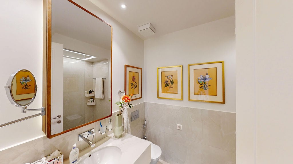 Modern bathroom in an apartment, Luštica, Montenegro: light tiles, a large mirror, and wall decor.