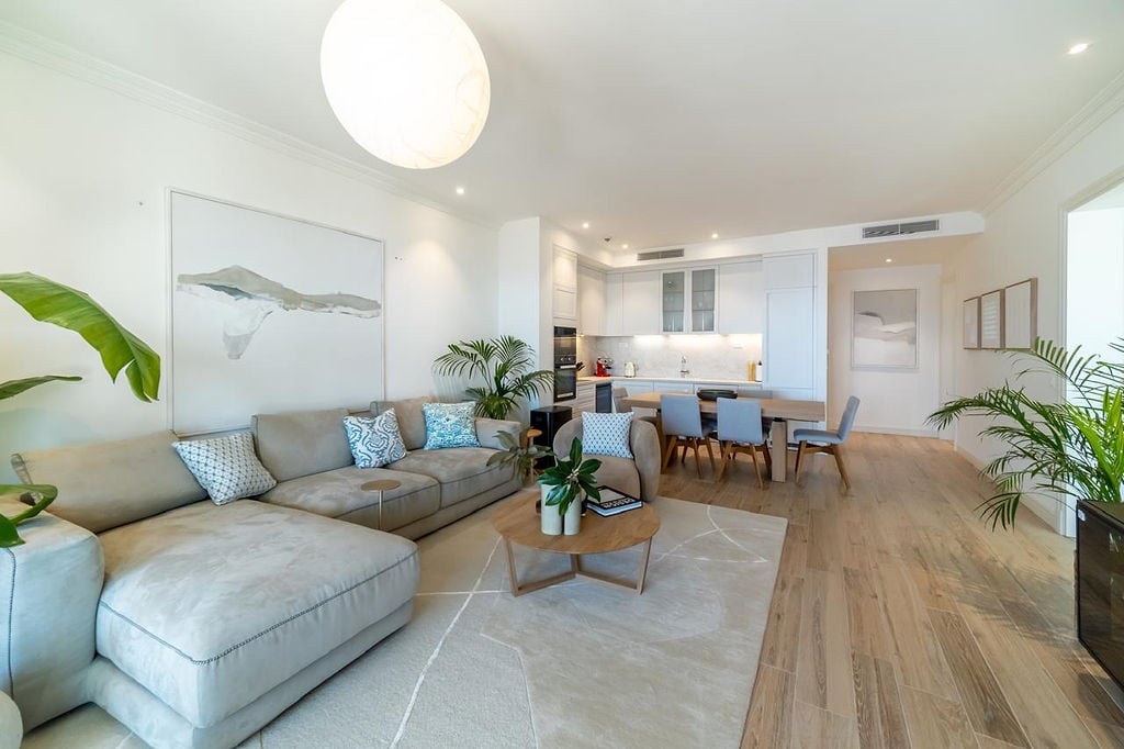 Modern living room with kitchen in an apartment in Luštica, Montenegro: bright interior, soft sofa, and dining area.