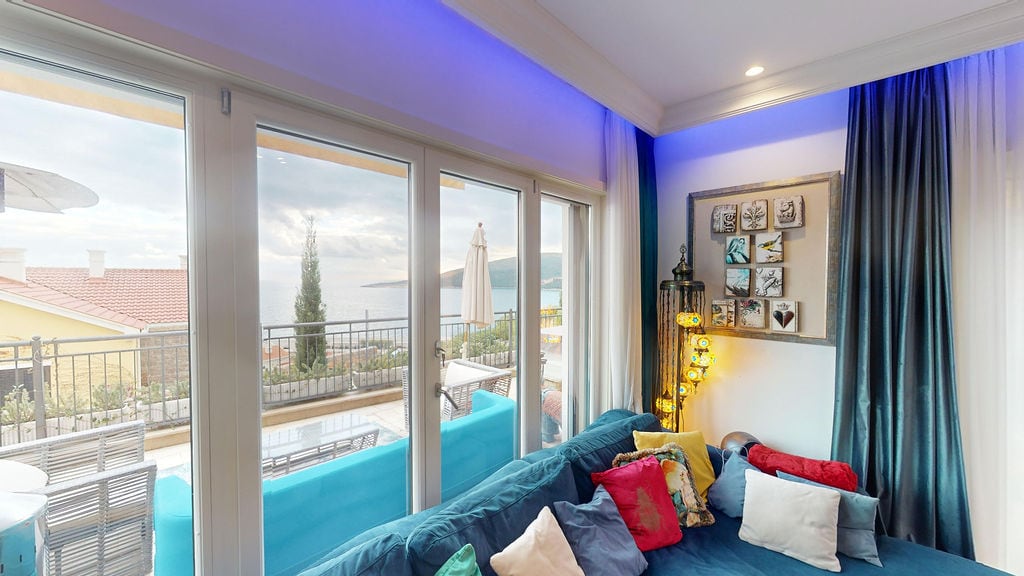Living room with panoramic sea view in a townhouse, Luštica, Montenegro: blue sofa, terrace, and stylish interior.