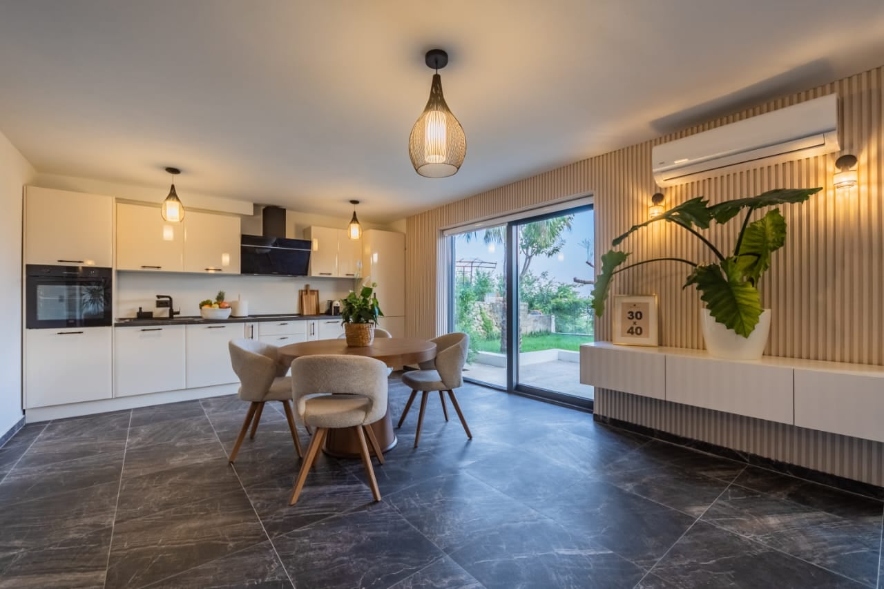 Modern kitchen-living room with a dining area in a villa in Budva, Montenegro: stylish interior, access to the terrace.