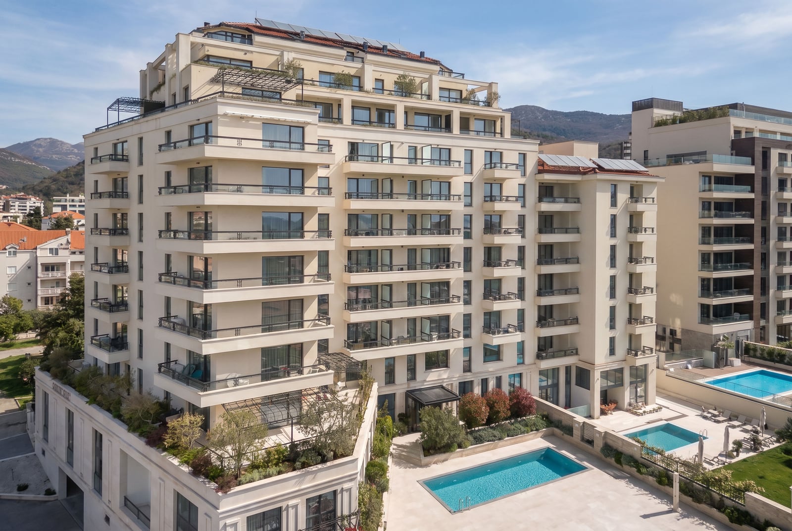 Modern residential complex with swimming pools and terraces in Bečići, Montenegro: view of the building facade and the surrounding grounds