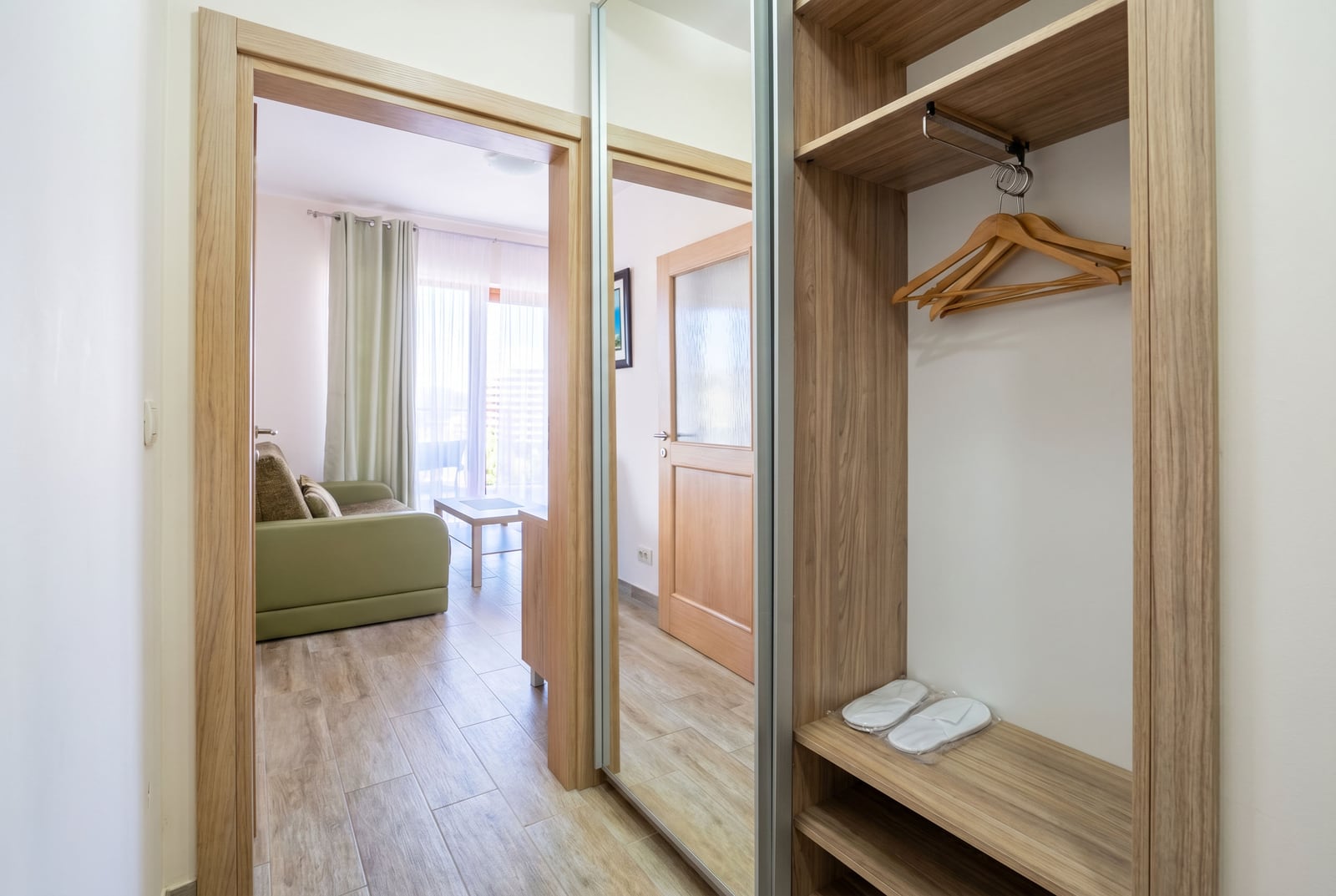 Entrance hall with a built-in wardrobe and a view of the living room in an apartment, Bečići, Montenegro: bright interior, wood-finish furniture.