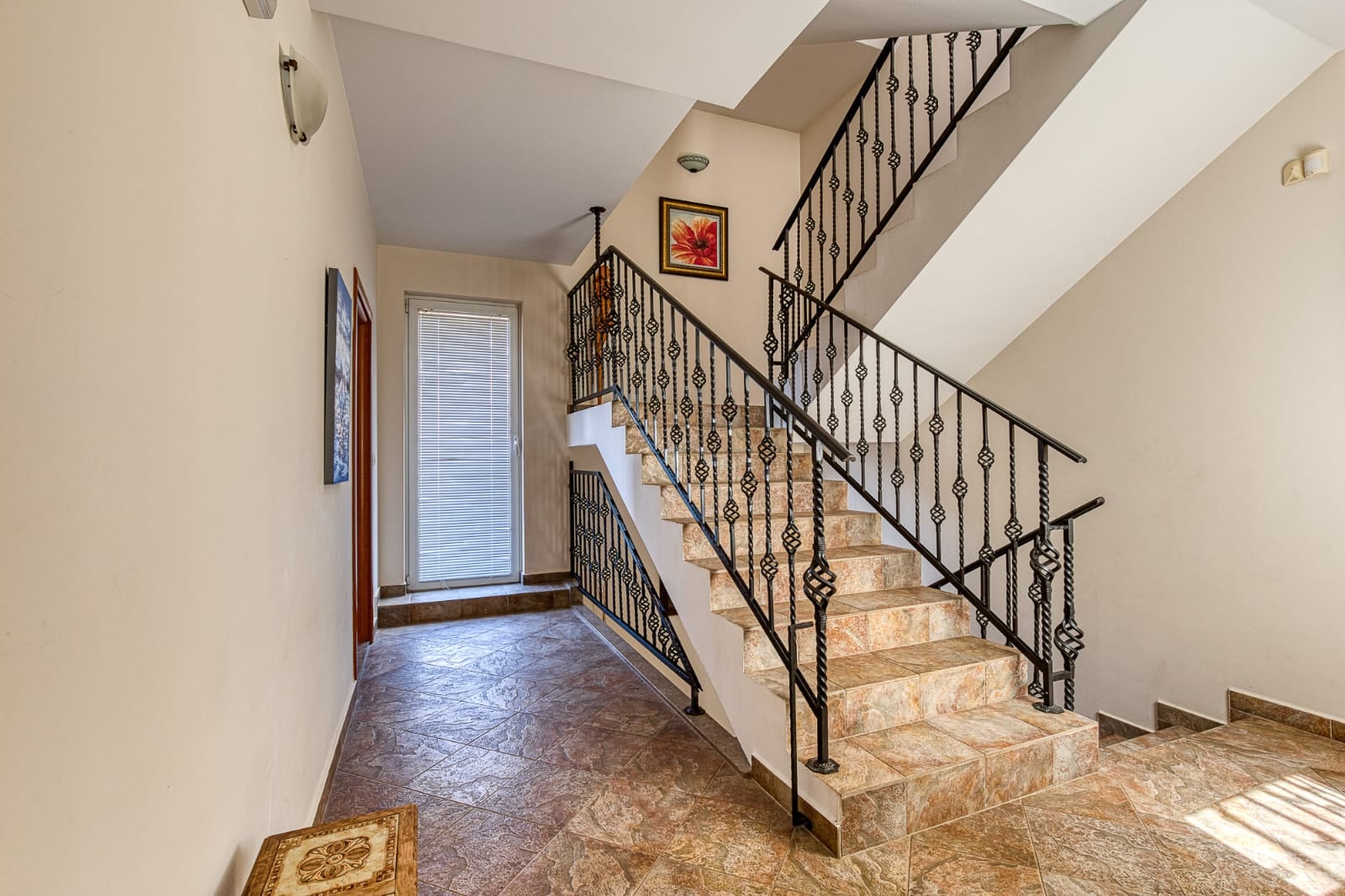 Staircase with wrought iron railings and tile finishes in a villa interior in Becici, Montenegro.