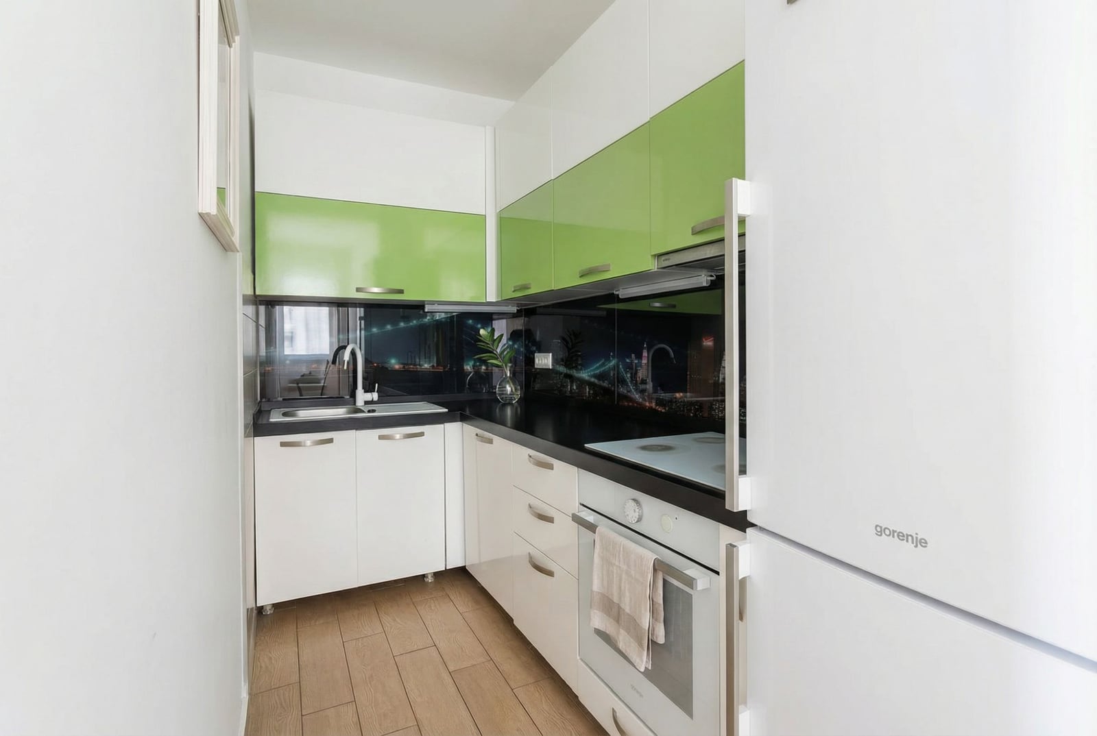 Modern kitchen in an apartment in Pržno, Montenegro: white cabinetry with green fronts and built-in Gorenje appliances.