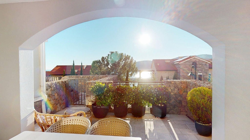 Stone-decorated terrace with sea view in the Luštica residential complex, Montenegro: wicker furniture and plants.