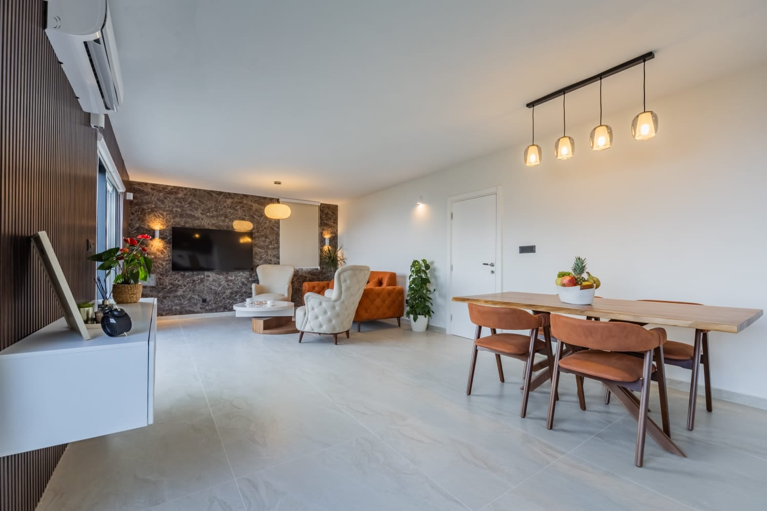 Modern living room with a dining area in a villa in Budva, Montenegro: stylish furniture, marble wall, and decor.