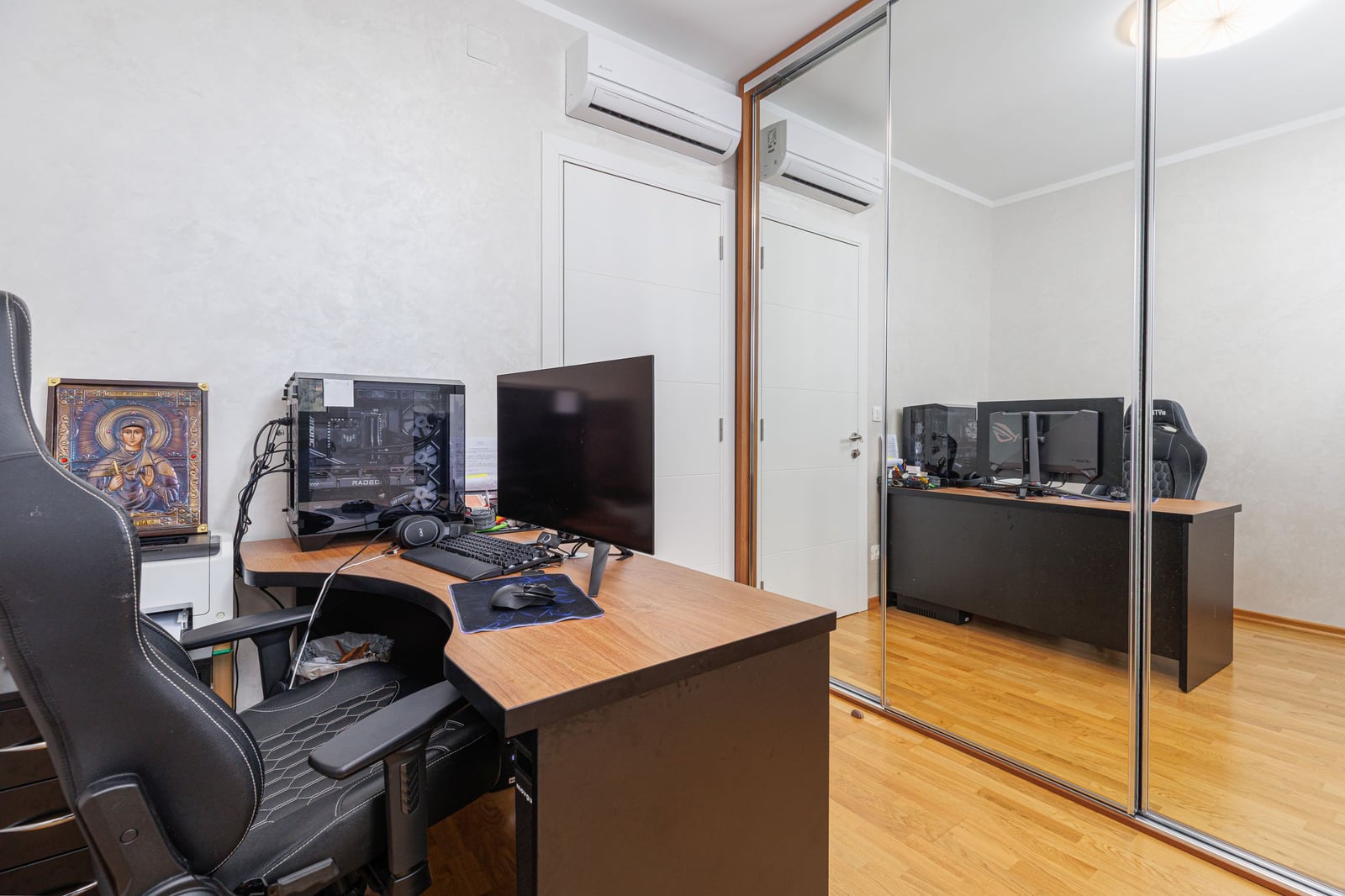 Home office in a penthouse in Bečići, Montenegro: computer desk, gaming chair, and mirrored sliding-door wardrobe.