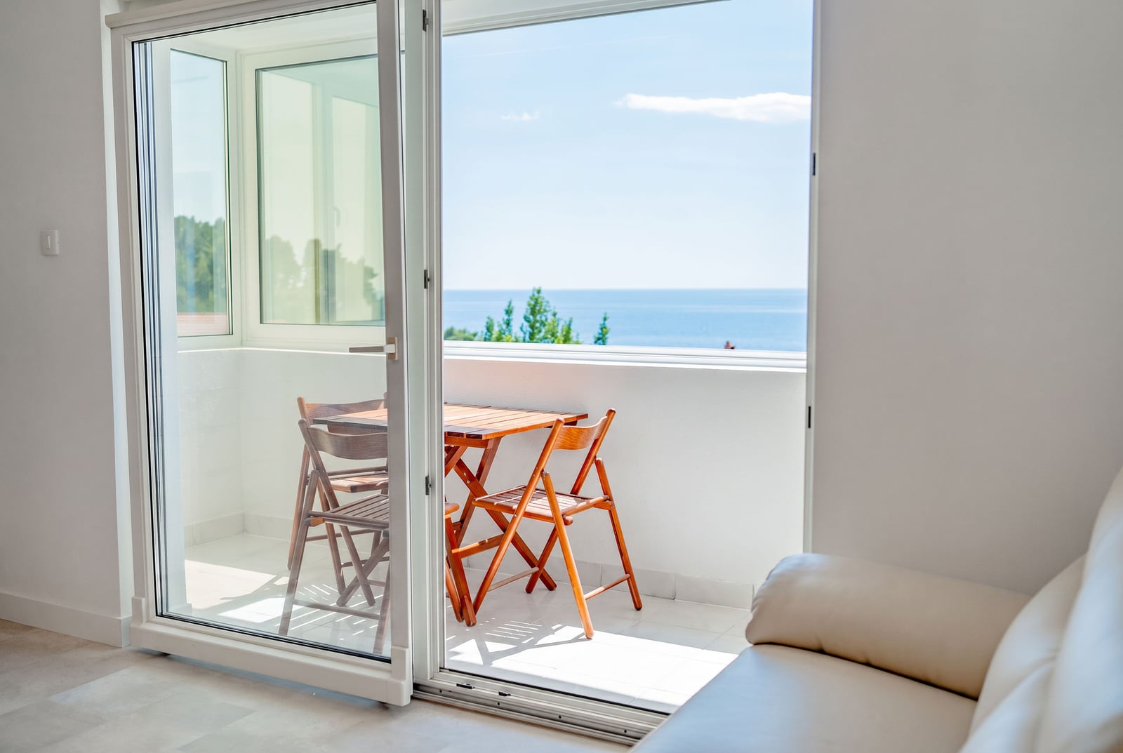 Balcony with a wooden table and sea view in an apartment in Sveti Stefan, Montenegro, with access from the bright living room.