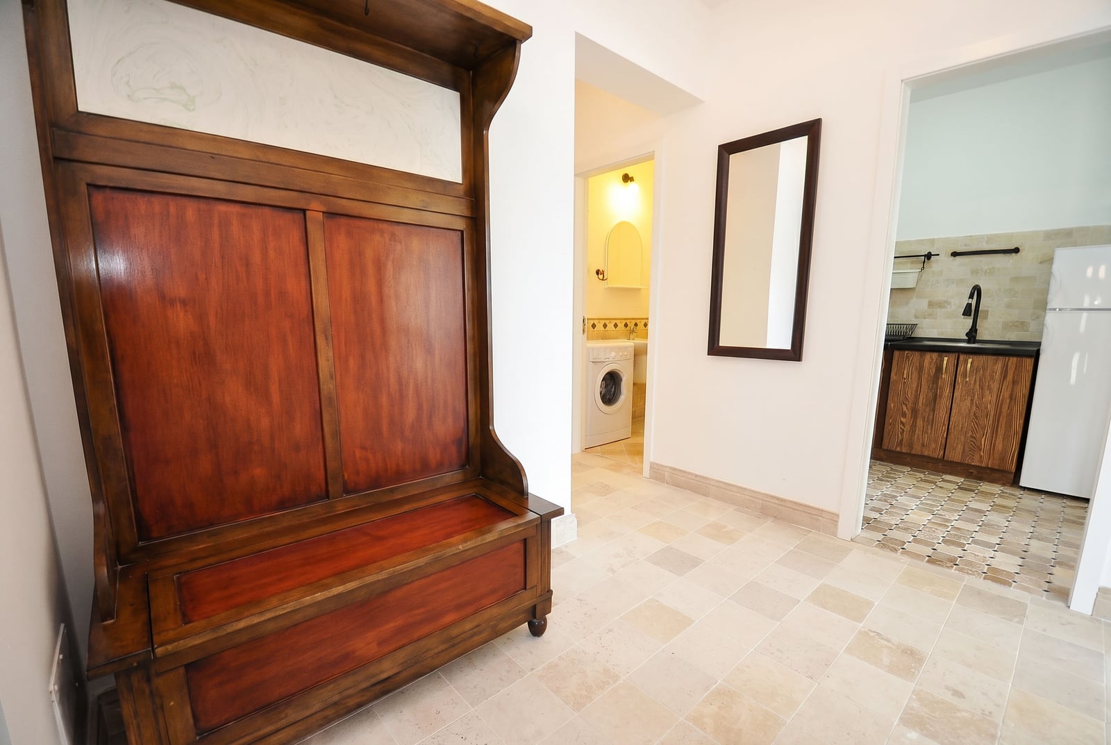 Entrance hall with wooden furniture, mirror, and view of the kitchen in an apartment in Risan, Montenegro.