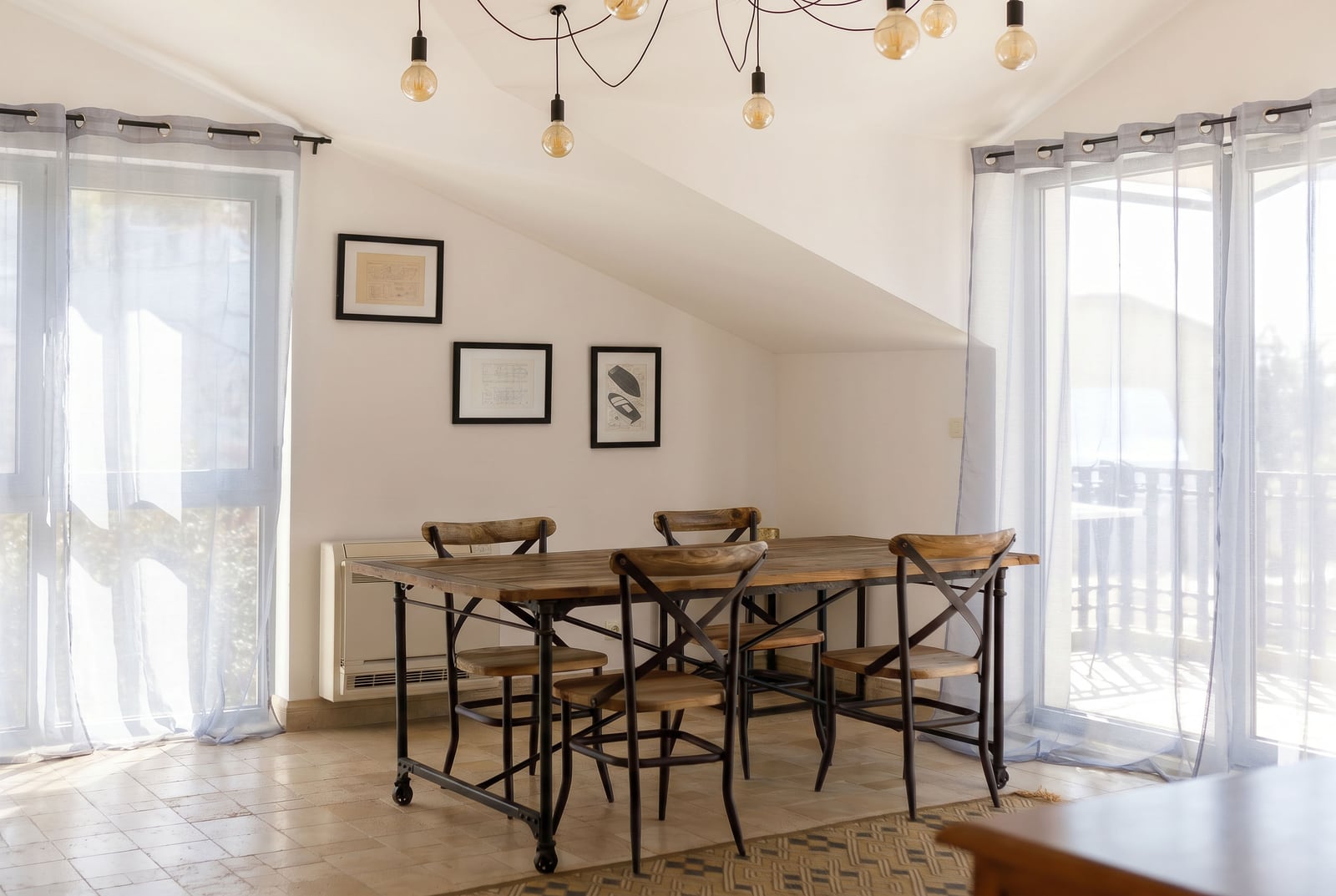 Dining area in a penthouse in Risan, Montenegro: a wooden loft-style table, panoramic windows, and stylish lighting.