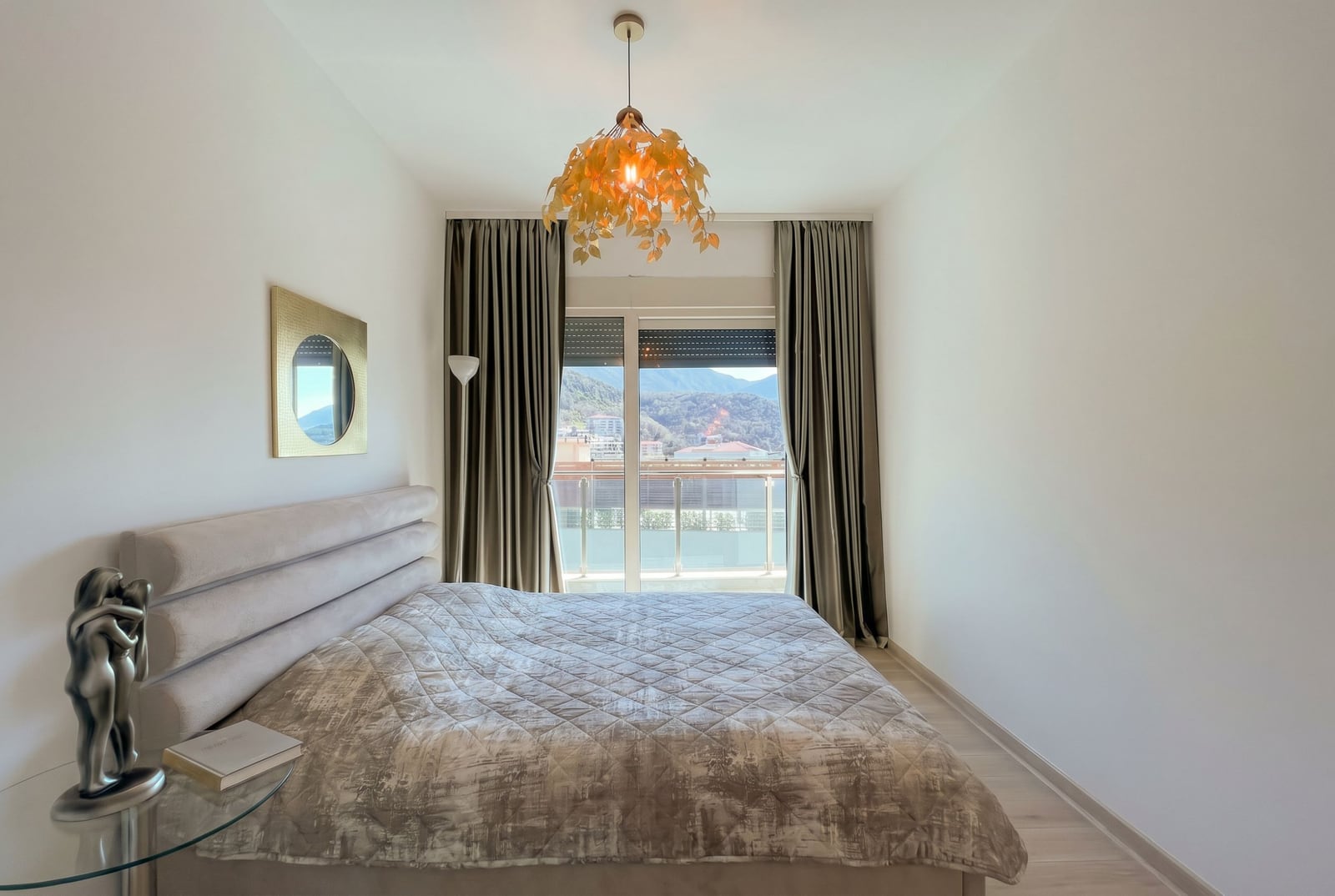 Cozy bedroom with a double bed and mountain views in an apartment in Becici, Montenegro. Modern interior design.