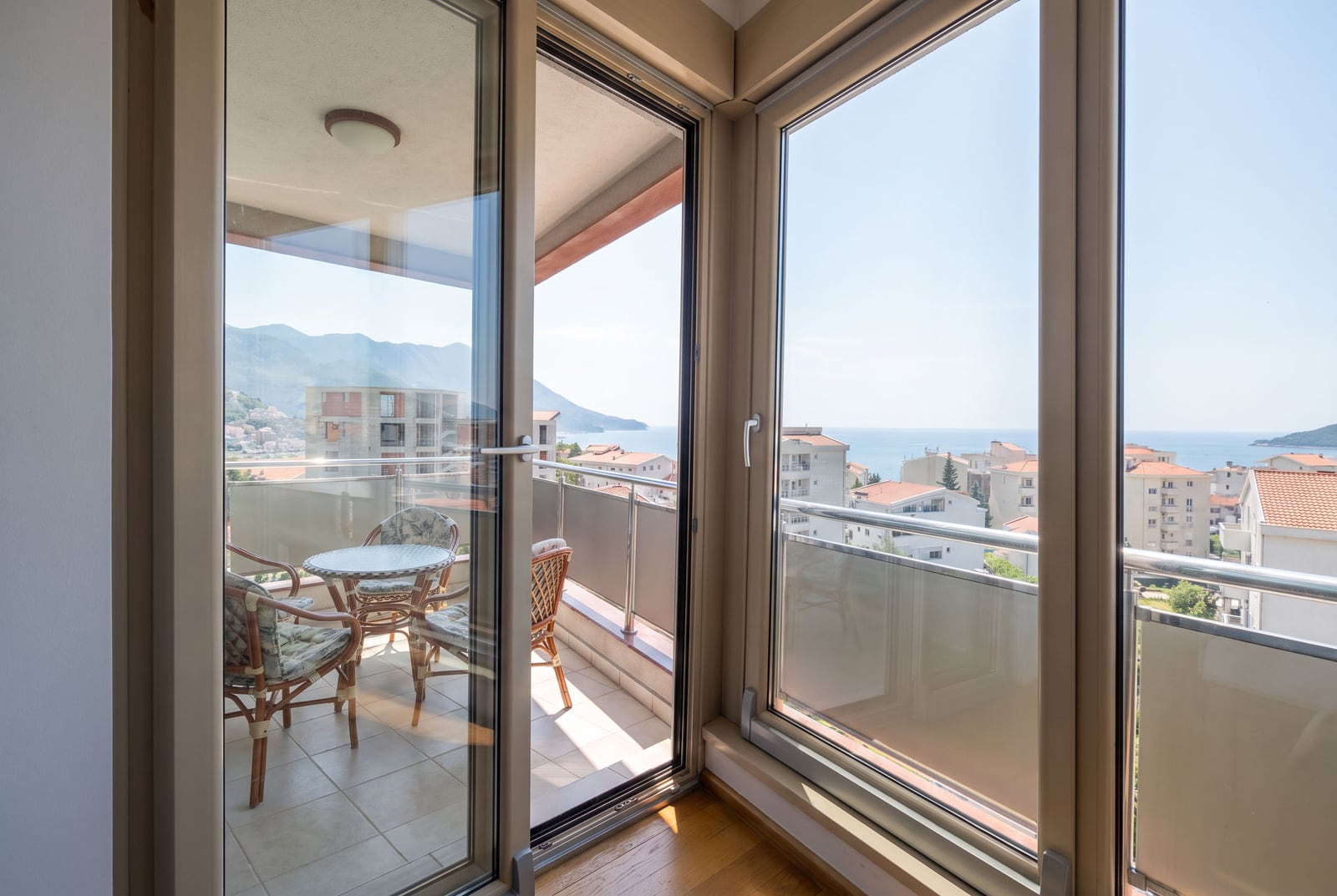 Panoramic windows and a furnished balcony with sea views in an apartment in Bečići, Montenegro.