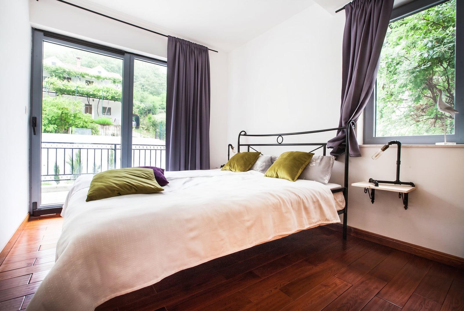 Bedroom with a double bed, panoramic windows, and a mountain view in an apartment in Risan, Montenegro.