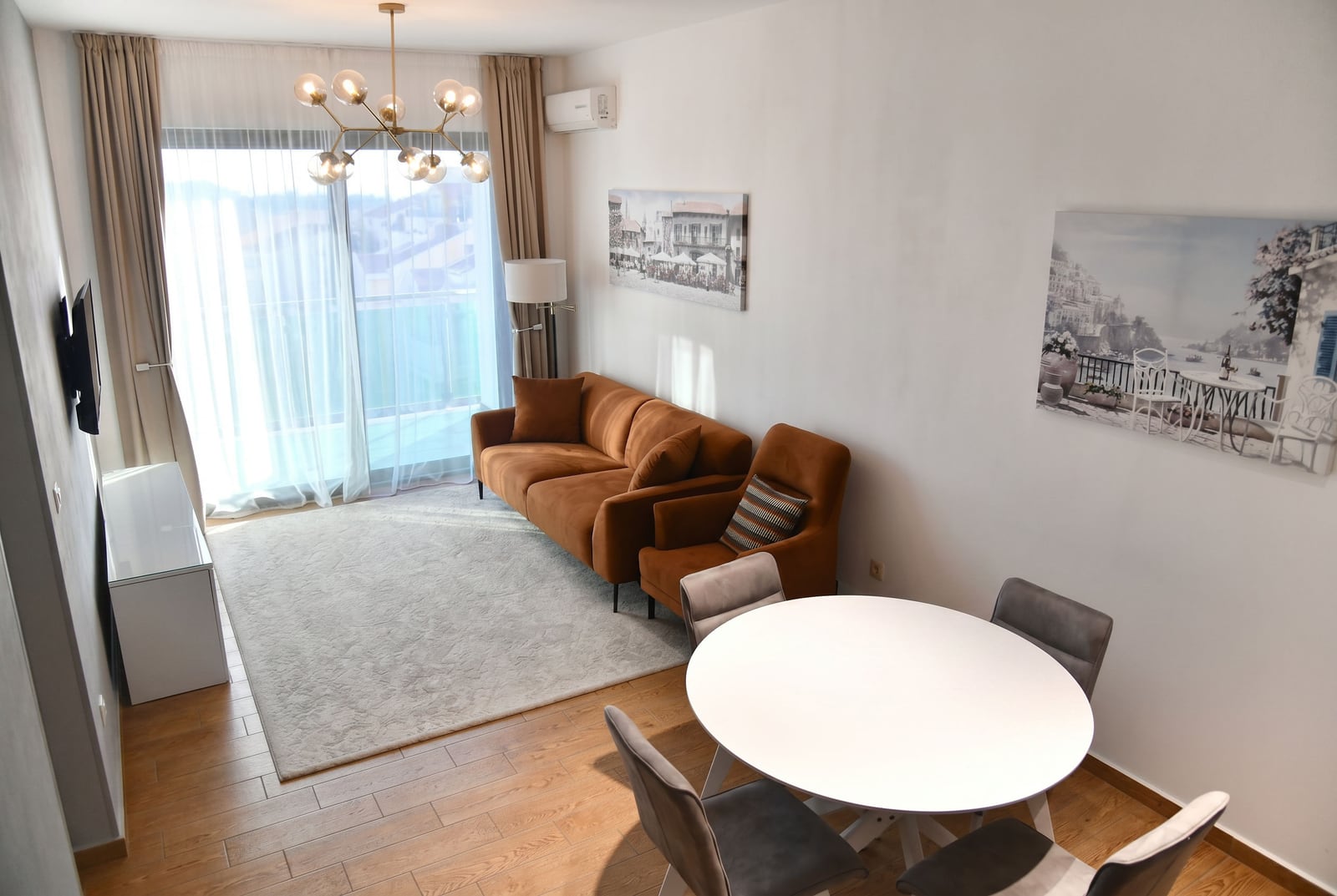 Modern living room with a brown sofa and dining area in an apartment, Bečići, Montenegro. Panoramic window and decor.