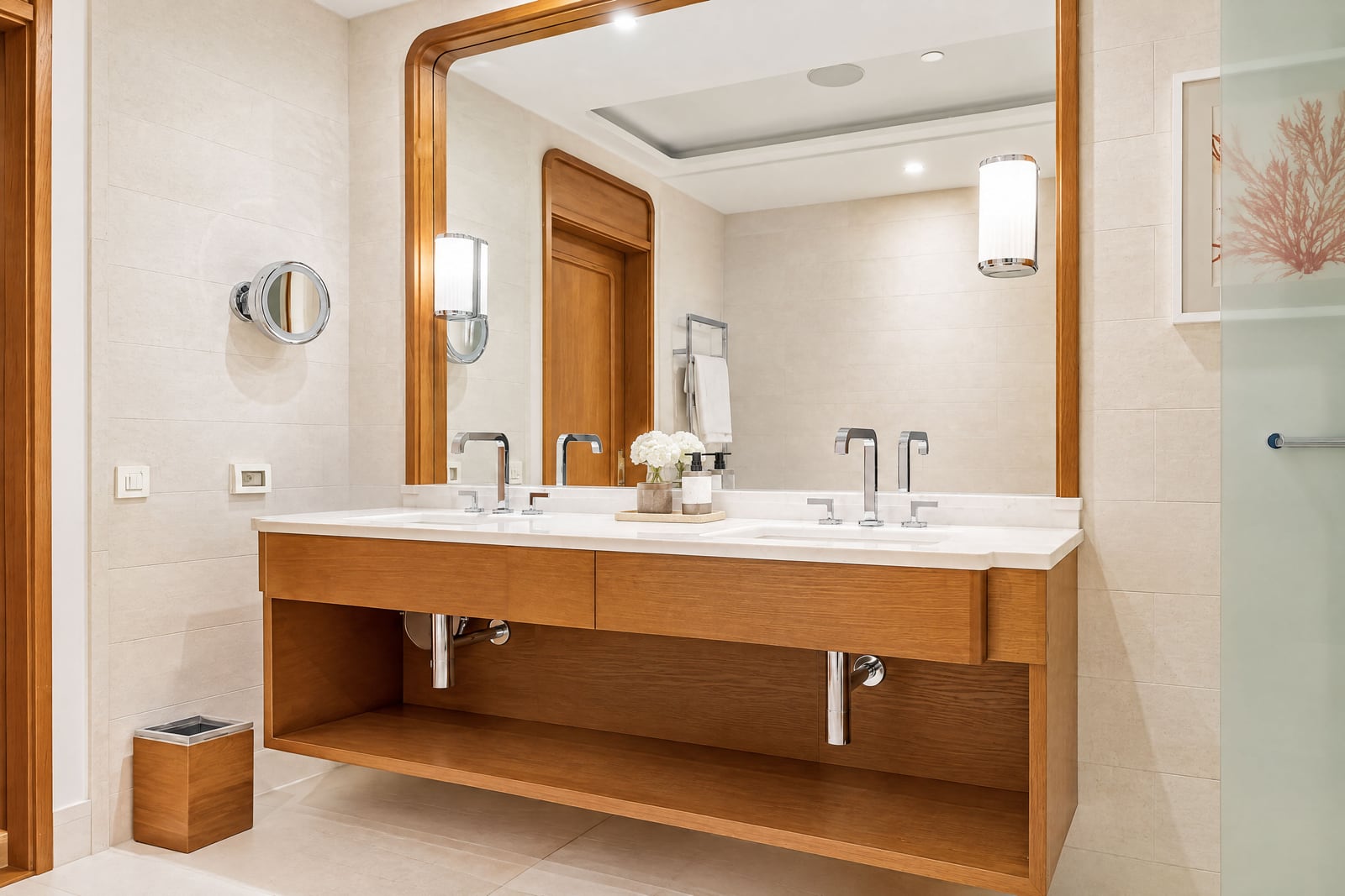 Modern bathroom featuring a double sink vanity with wood cabinetry, large framed mirror, and tiled walls.