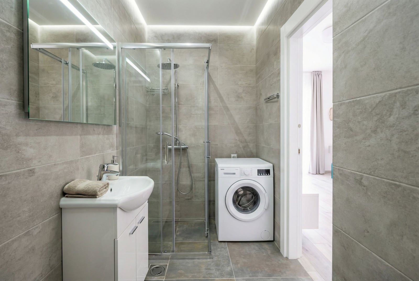 Modern bathroom with a shower cabin and washing machine in an apartment, Becici, Montenegro.
