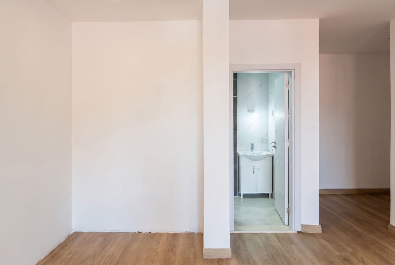 Bright living room with laminate flooring and an entrance to the bathroom in a new apartment in Budva, Montenegro.