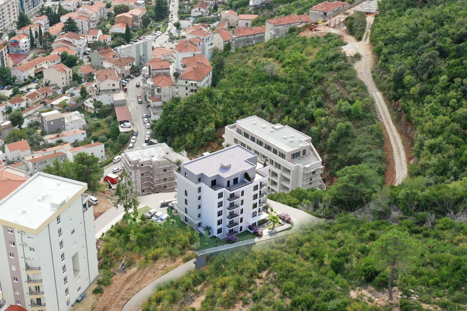 Aerial view of a modern residential complex in Budva, Montenegro, surrounded by greenery and urban development.