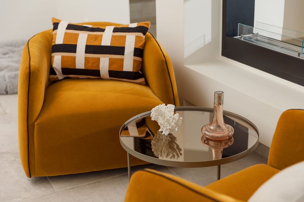 Cozy lounge area with mustard armchairs and a coffee table in the interior of a villa, Luštica, Montenegro.